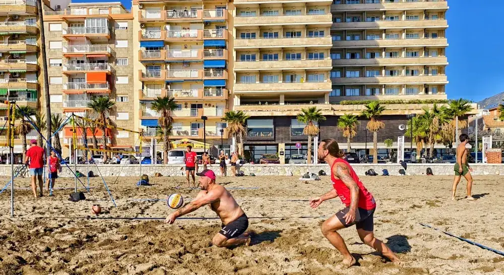 Jugador lanzándose a por el balón frente a los edificios del paseo